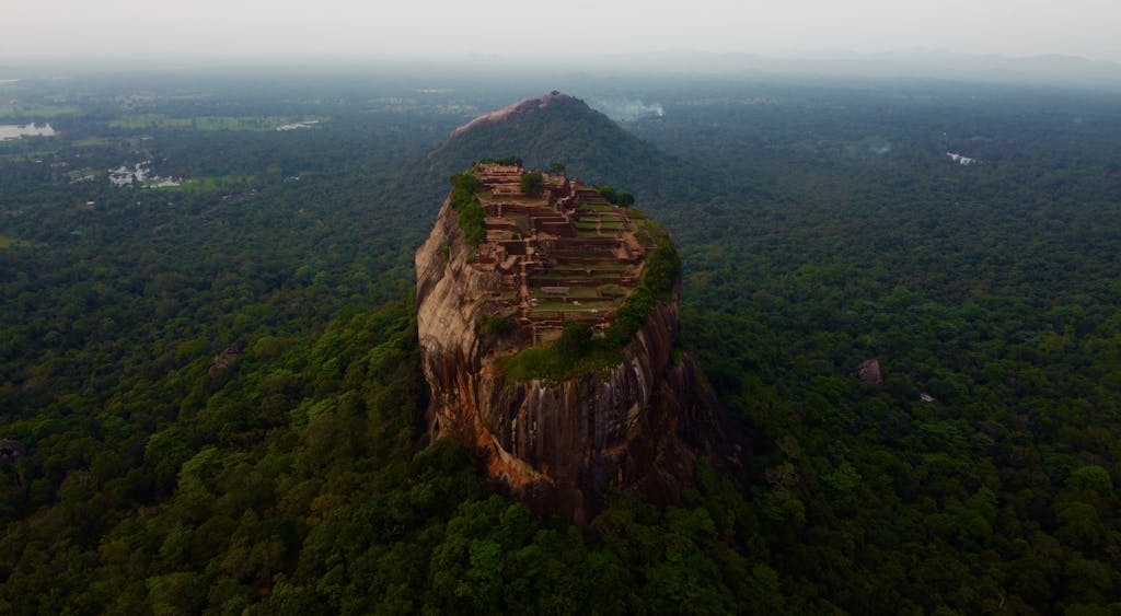 A stunning aerial view of Sigiriya Rock Fortress rising above lush greenery in Sri Lanka.
