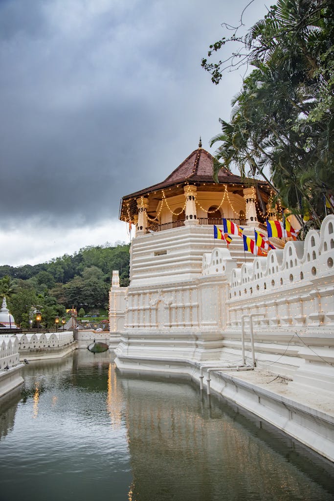 Beautiful view of a sacred temple reflecting in the river, surrounded by lush greenery, under a moody sky in Sri Lanka.