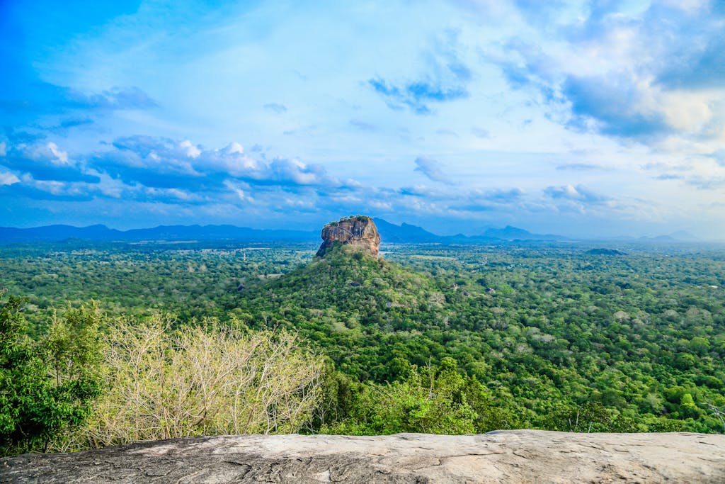 Breathtaking panoramic view of Sigiriya Rock amidst lush greenery in Sri Lanka under a vibrant sky.