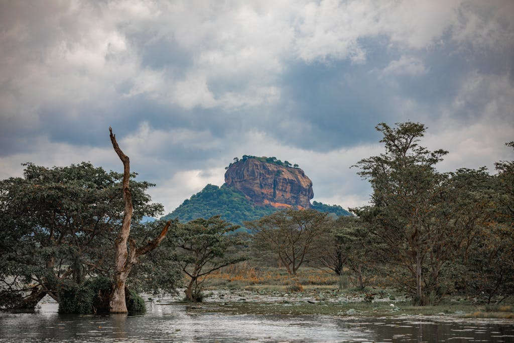 Majestic Sigiriya Rock amidst lush foliage and moody clouds in Sri Lanka.